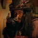 Jason Momoa, in a purple top hat, suit, and satyr horns, flips the "metal" sign.